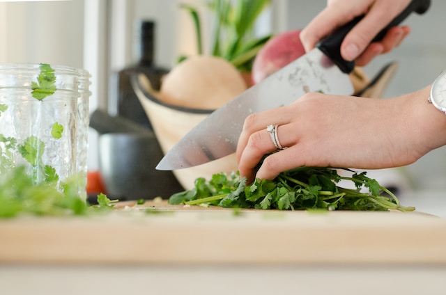 Close-up of hands chopping herbs.