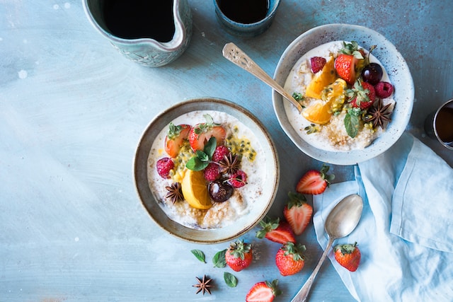 Two bowls of oats topped with an assortment of fruits.