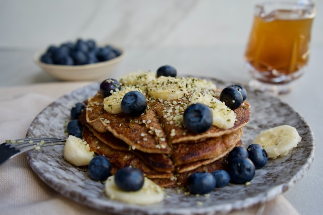A stack of pancakes with banana and blueberry toppings.