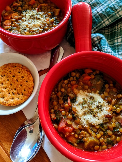 A pot and bowl filled with lentil soup served with a plate of biscuit.