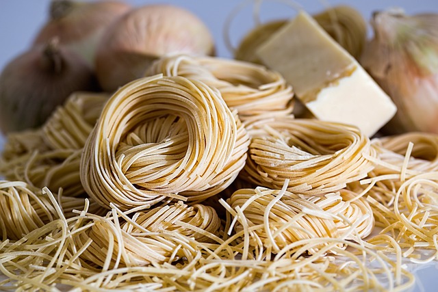 Uncooked noodles with onions in the background