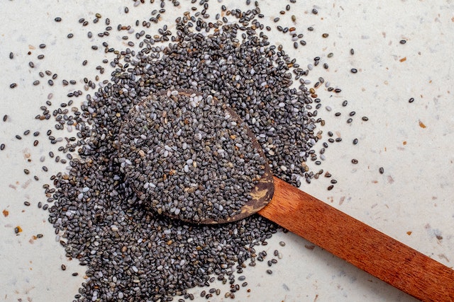 Raw chia seeds in a wooden spoon