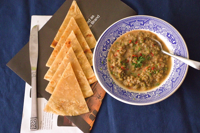 A plate of lentil soup served with toasted tortilla