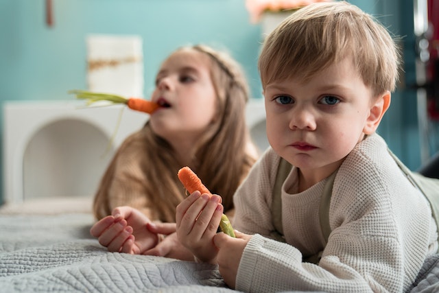 Two kids eating carrots