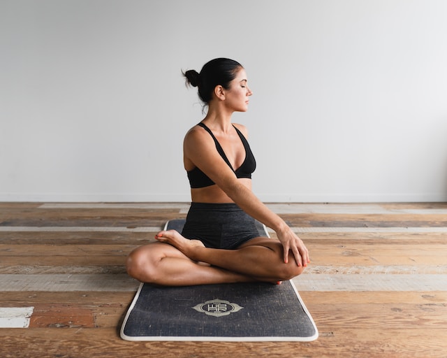 A woman sits cross-legged on a yoga mat