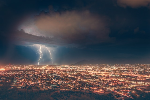 Lightning flashing across the sky above an urban landscape at nighttime 