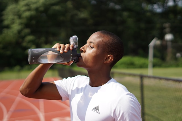 Person drinking from a water bottle on the track