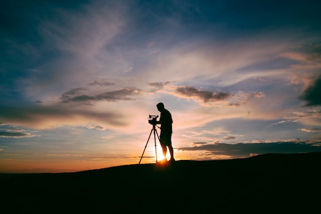 Silhouette of a photographer setting up his camera on a tripod