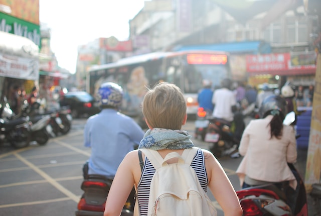 Woman wearing a backpack walking along a busy street