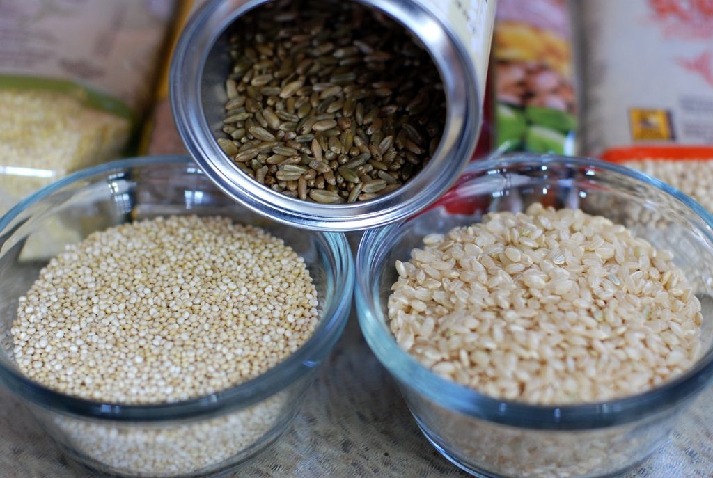 Black rice, white rice, and quinoa grains inside glass containers