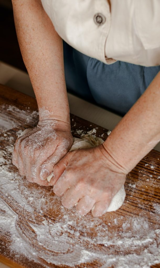 Pair of hands kneading dough on a wooden surface