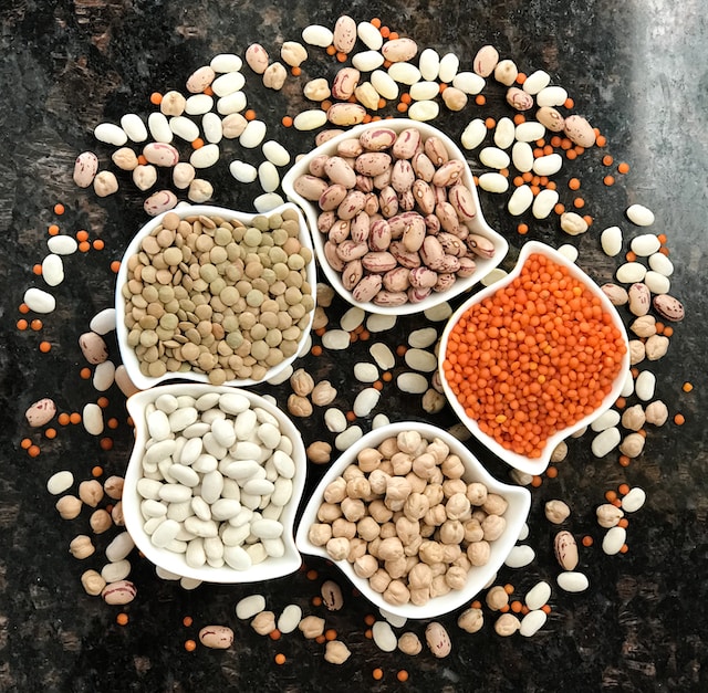 Lentils and beans inside small, oddly-shaped, white ceramic bowls