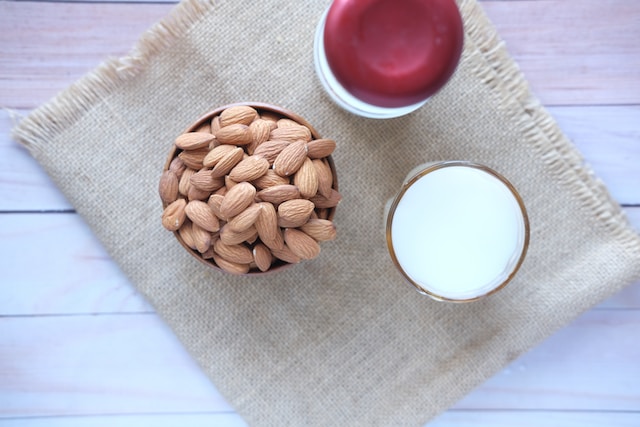 A bowl of almonds beside a glass of milk
