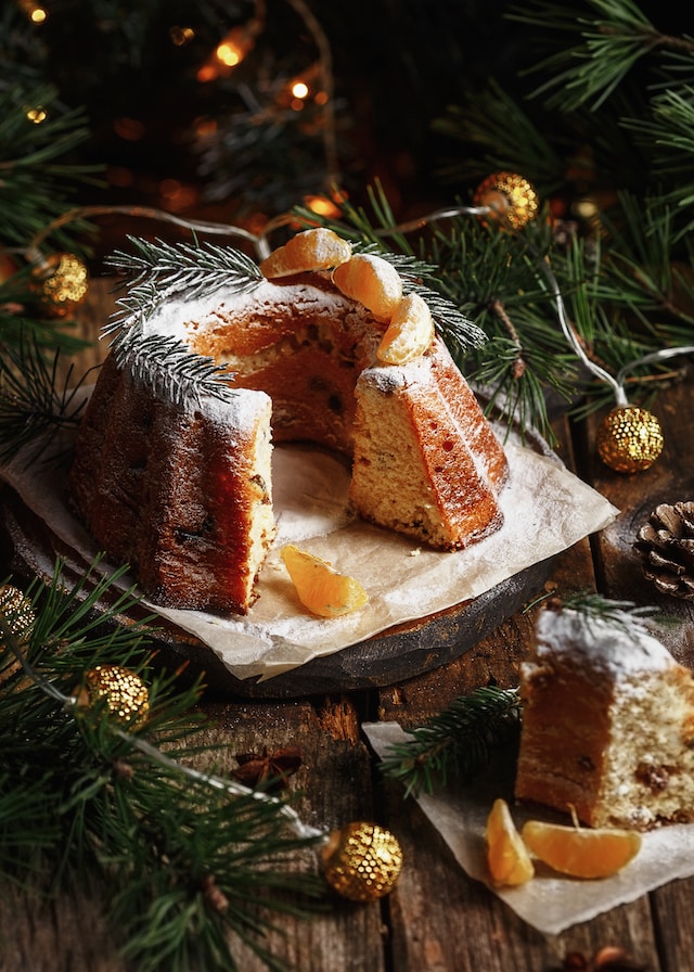 Festive looking fruit cake decked in pine leaves and oranges