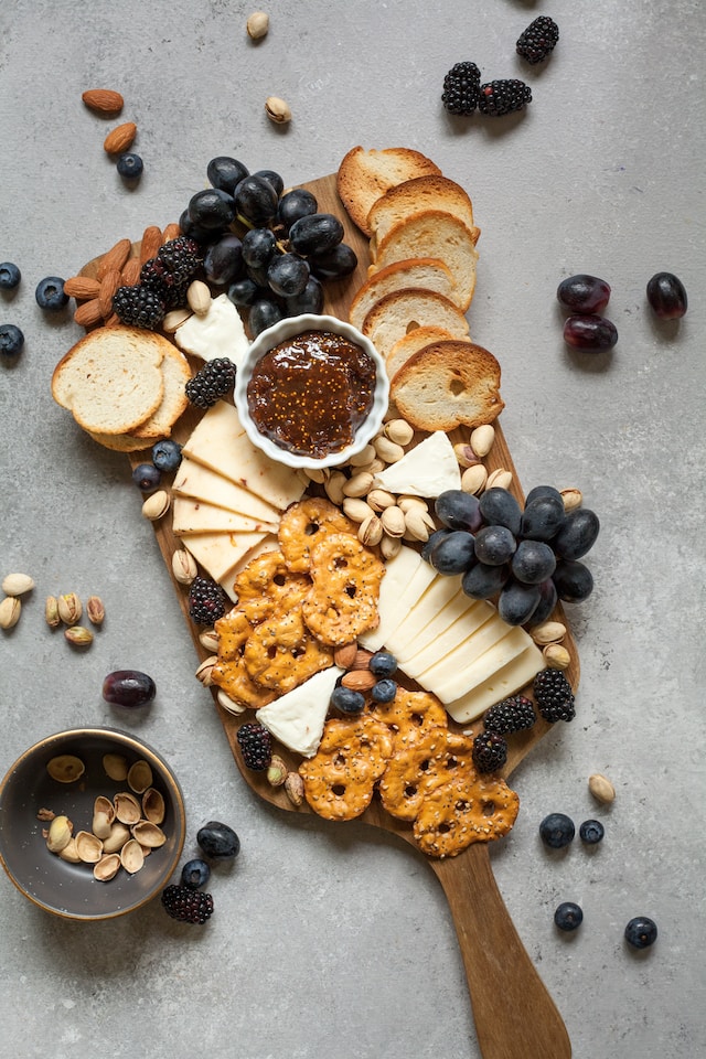 A cheese platter with bread slices and assorted fruits and nuts
