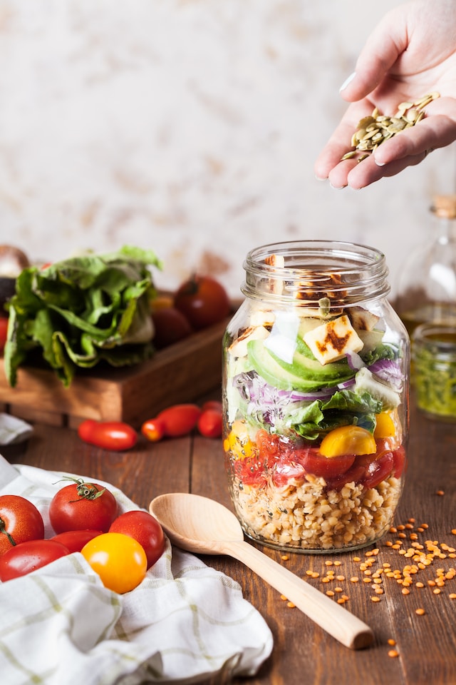 Person adding seeds to a prepped meal inside a mason jar